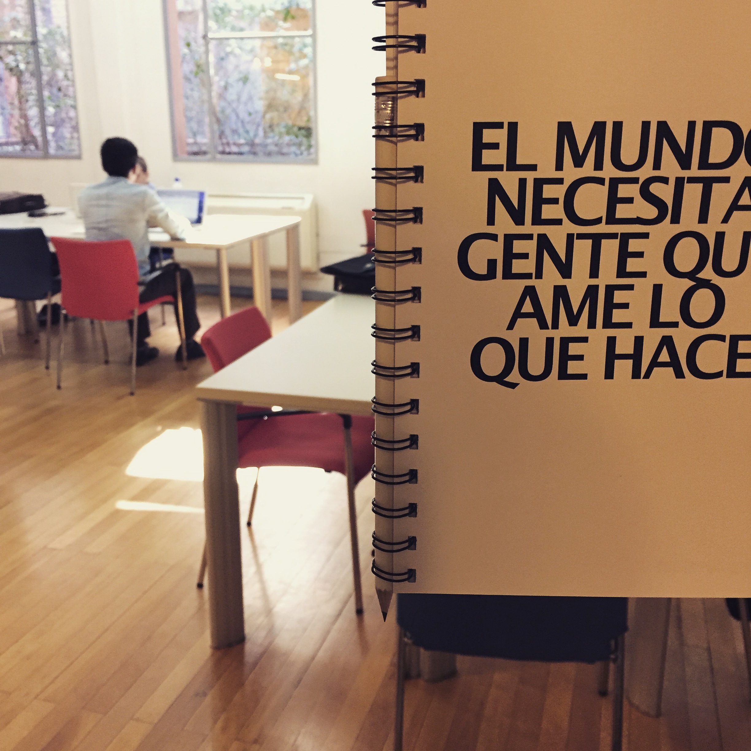 A photo of a notebook cover that reads El mundo necesita gente que ame lo que hace